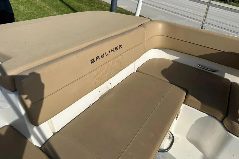 Slide: The Image of 2021 Bayliner VR6 Bowrider OB with tan seating and logo, parked on grass. - 11