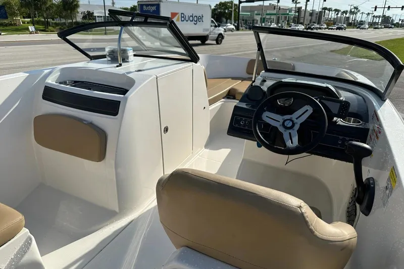 Slide: The Image of 2021 Bayliner VR6 Bowrider OB interior with steering wheel and seating, parked near a road. - 14