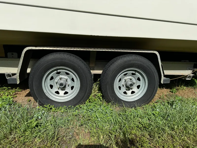 Slide: The Image of Trailer wheels of a 2002 Edgewater 260 Center Console boat on grass. - 26