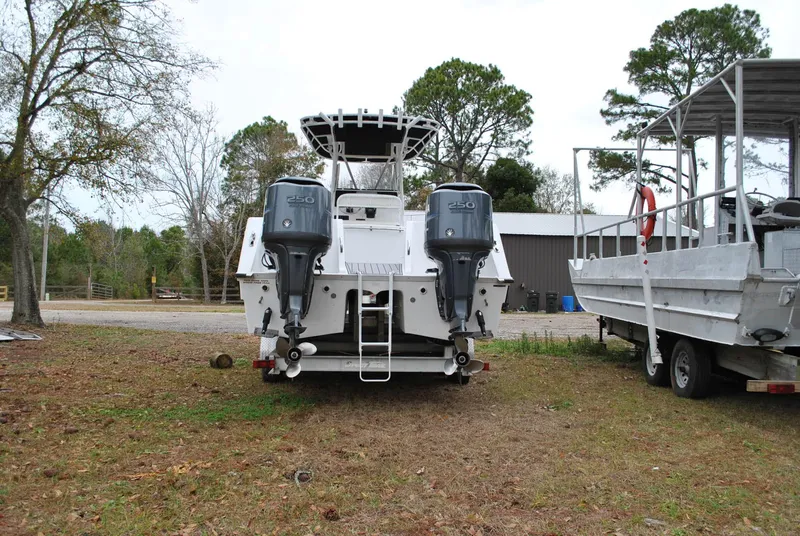 Slide: The Image of 2001 ProKat 2800KAT boat with dual outboard motors, parked on grass near trees and a trailer. - 23