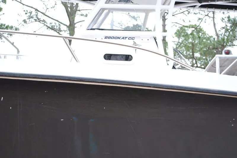 Slide: The Image of 2001 ProKat 2800KAT boat, side view with visible railing and trees in the background. - 29