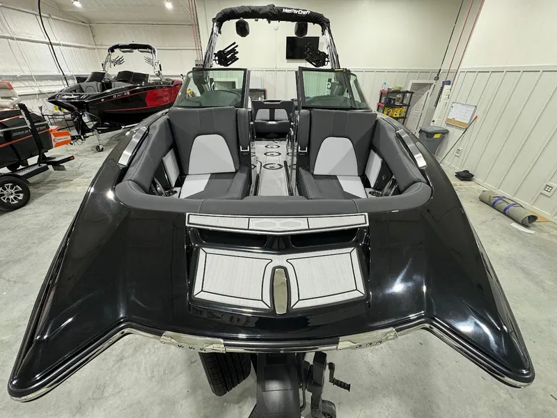 Slide: The Image of 2024 MasterCraft X22 boat interior in showroom, black and gray seating. - 12