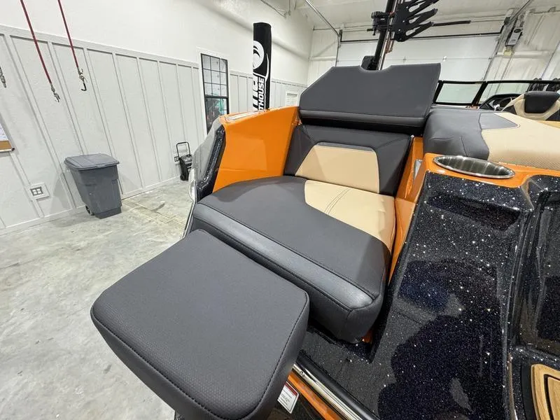 Slide: The Image of 2024 MasterCraft XStar S boat interior with orange and black seating in a garage. - 12