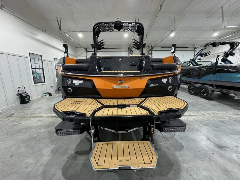 Slide: The Image of 2024 MasterCraft XStar S boat in showroom, rear view with teak swim platform. - 2