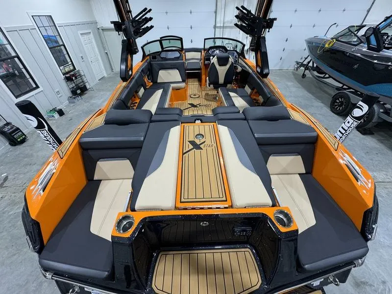 Slide: The Image of 2024 MasterCraft XStar S boat interior with orange and black seating in a garage. - 8