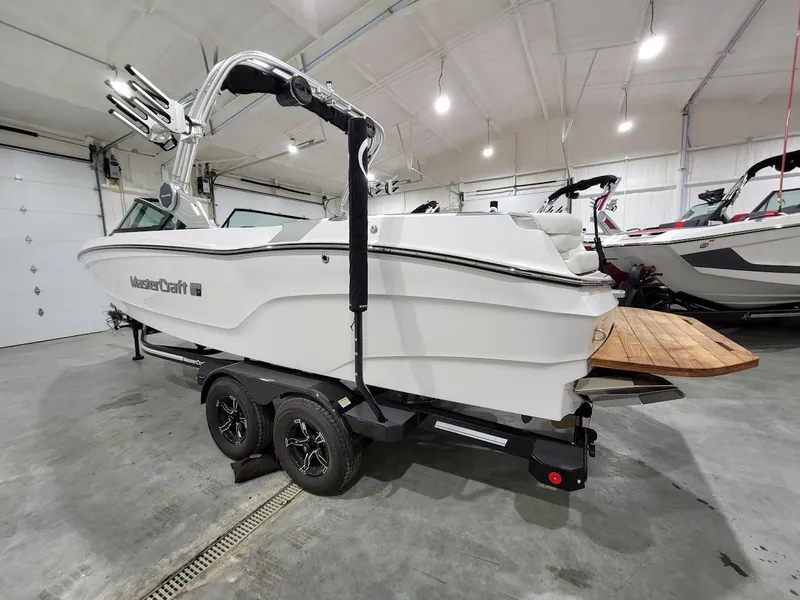 Slide: The Image of 2024 MasterCraft XT24 boat in a showroom, side view with trailer. - 8