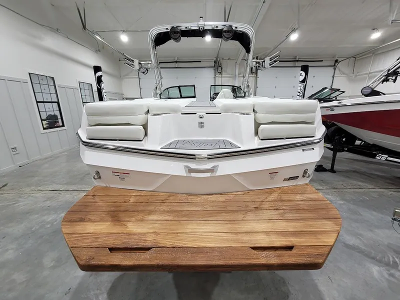 Slide: The Image of 2024 MasterCraft XT24 boat in showroom, rear view with wooden swim platform. - 9
