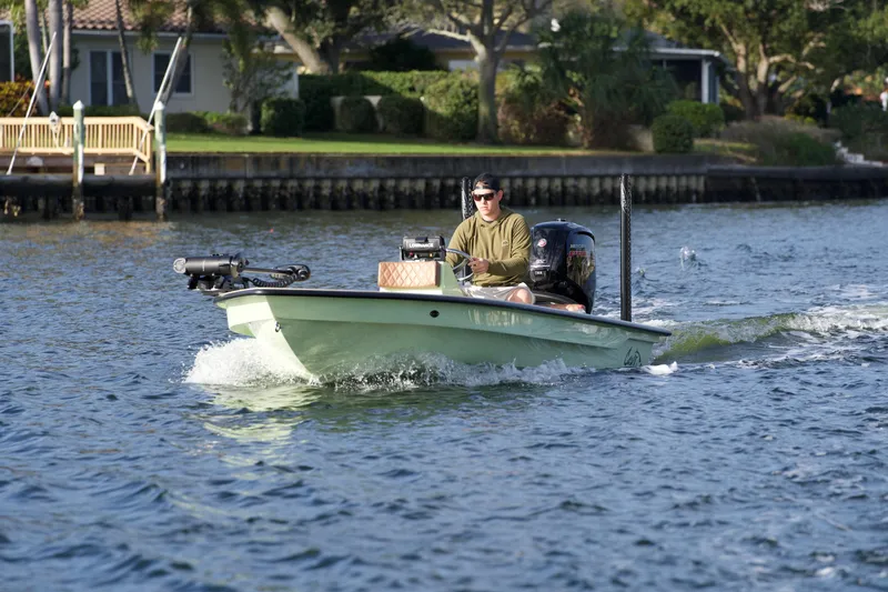Slide: The Image of 2023 Cayo Boatworks 180 model cruising on a calm river with a person at the helm. - 27