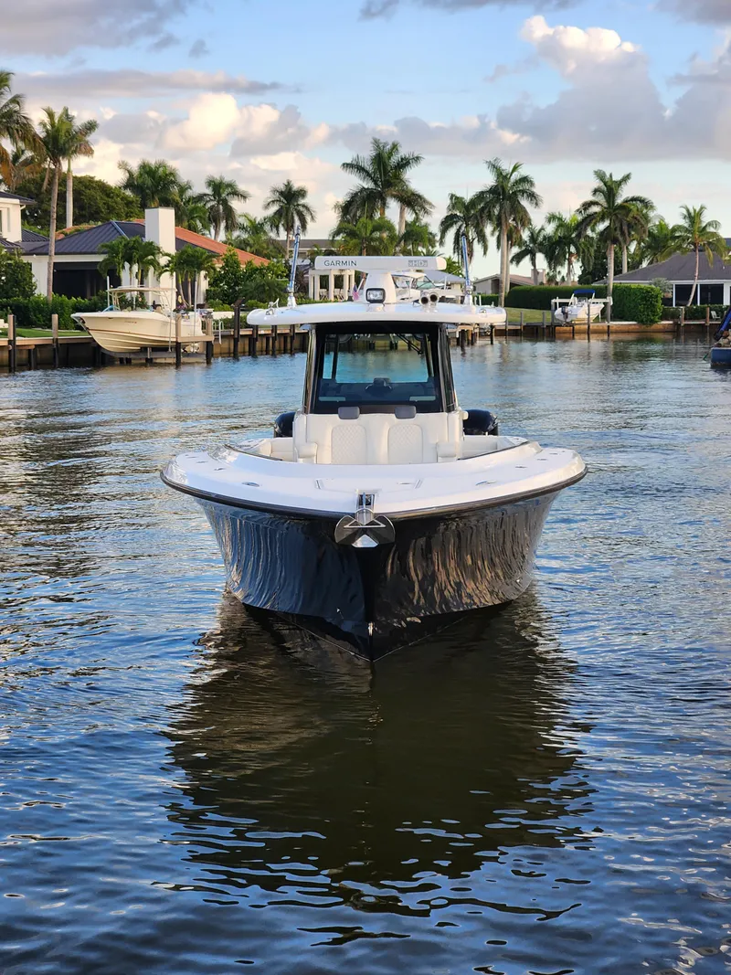 Slide: The Image of 2019 HCB 39 Speciale boat on calm water, surrounded by palm trees and waterfront homes. - 10