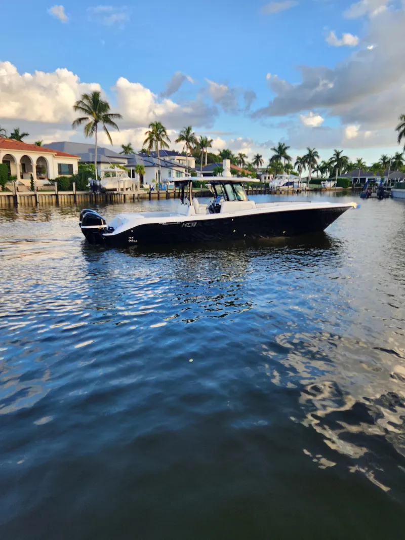 Slide: The Image of 2019 HCB 39 Speciale boat cruising on a scenic waterway with palm trees and houses. - 6