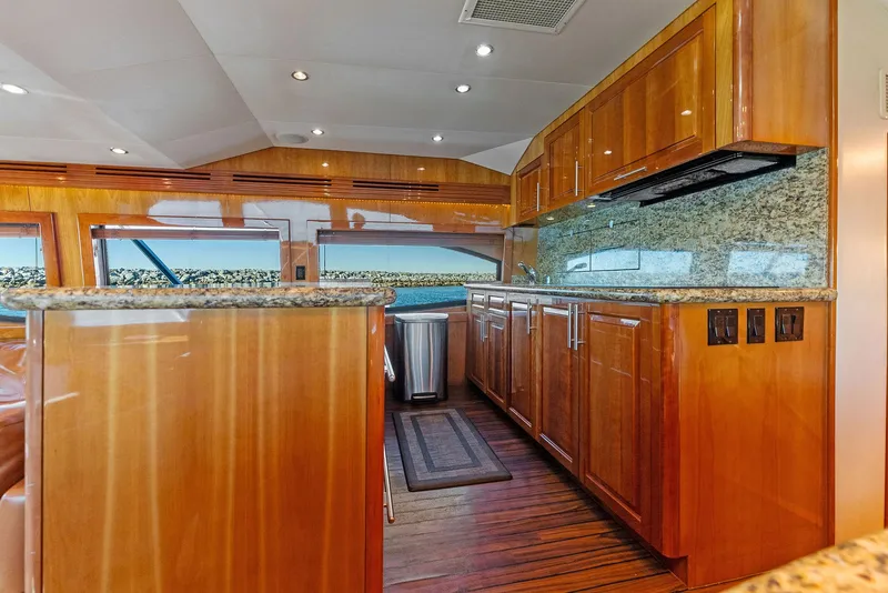 Slide: The Image of Luxurious kitchen interior of a 2007 Hatteras 64 Convertible yacht with wooden cabinetry and granite countertops. - 13