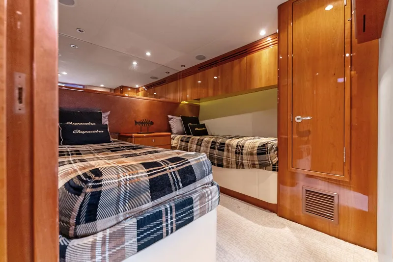 Slide: The Image of 2007 Hatteras 64 Convertible cabin with twin beds and wooden cabinetry. - 22