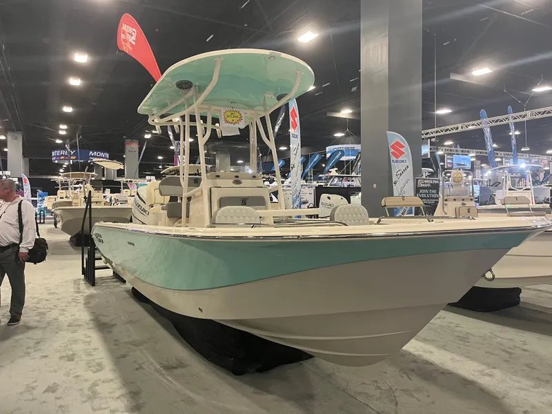 Slide: The Image of 2024 Carolina Skiff 24 Ultra Elite boat on display at an indoor boat show. - 17