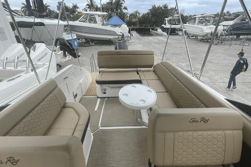 Slide: The Image of 2019 Sea Ray SDX 250 Outboard boat interior with beige seating and table, docked at marina. - 19