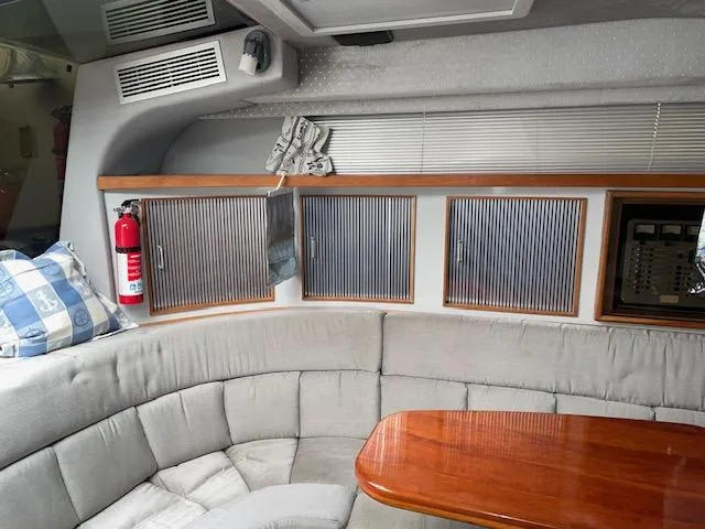 Slide: The Image of Interior of 1989 Sea Ray 390 Express Cruiser with cushioned seating and wooden table. - 29