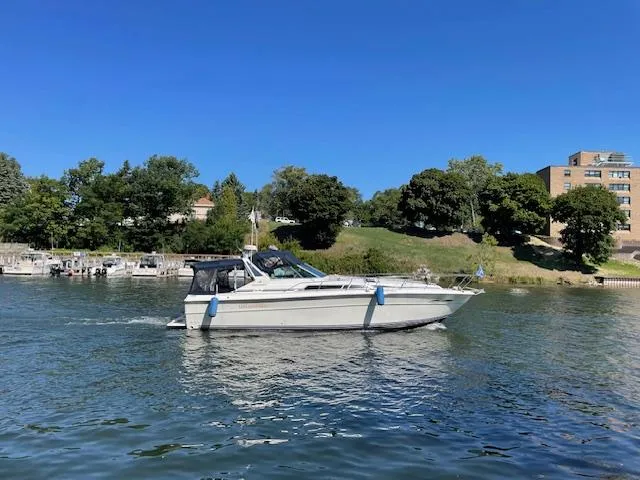 Slide: The Image of 1989 Sea Ray 390 Express Cruiser on a calm lake with a scenic shoreline. - 3