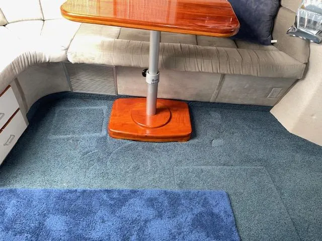 Slide: The Image of Interior of 1989 Sea Ray 390 Express Cruiser with wooden table and blue carpet. - 30