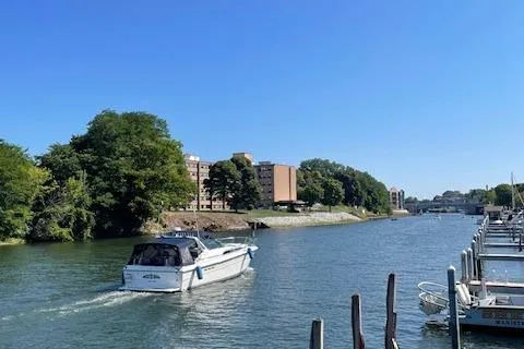Slide: The Image of Sea Ray 390 Express Cruiser (1989) navigating a serene river with buildings and docks in the background. - 8