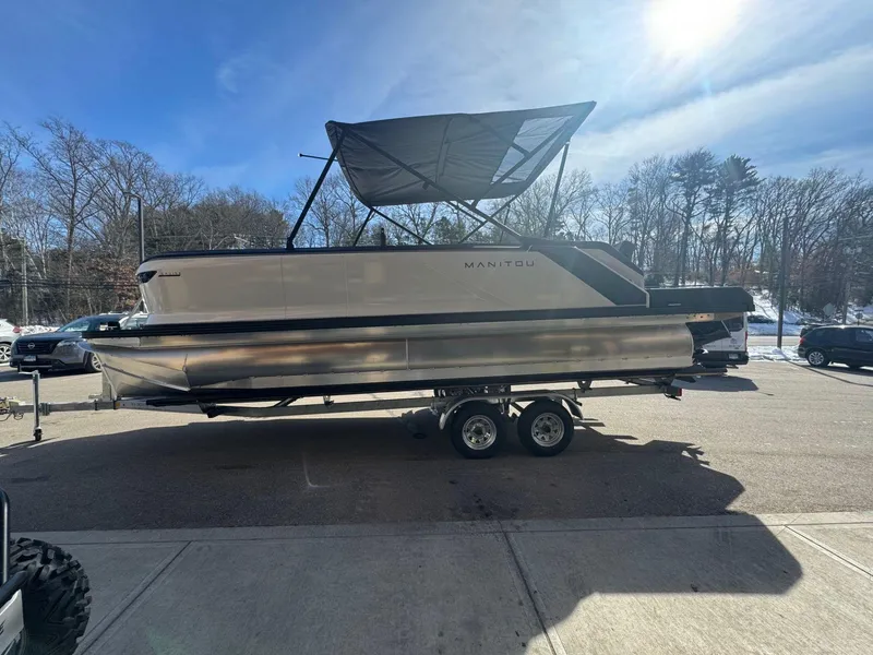 Slide: The Image of 2024 Manitou Cruise 22 Max Bench pontoon boat on a trailer. - 2