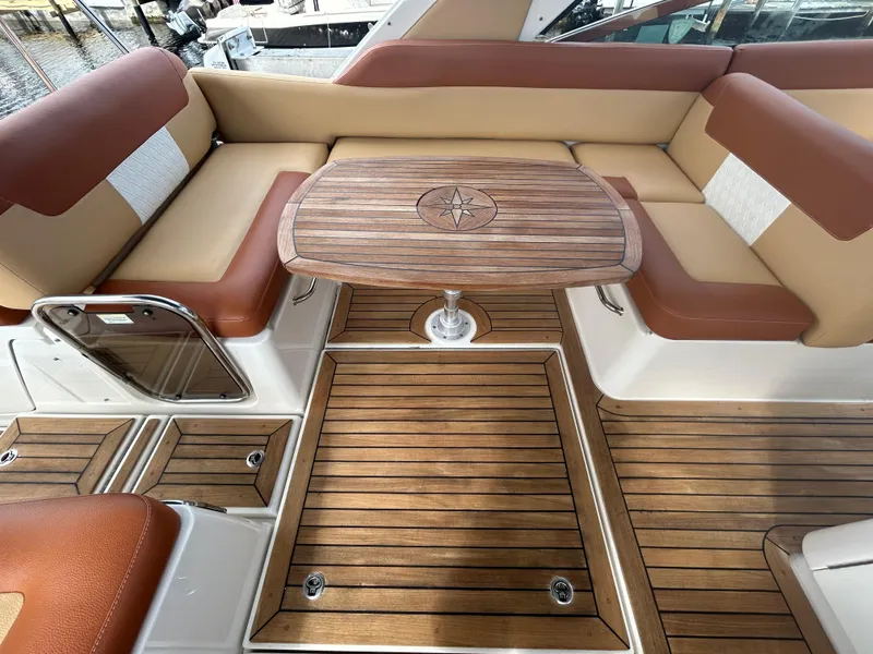 Slide: The Image of 2014 Sea Ray 370 Venture boat interior with wooden table and cushioned seating. - 27