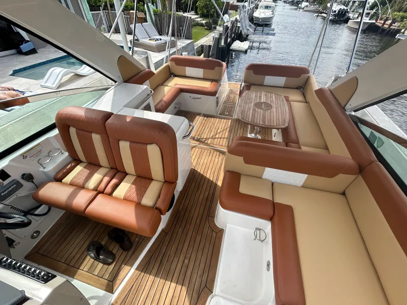 Slide: The Image of 2014 Sea Ray 370 Venture boat interior with tan and brown seating, wooden deck, and waterfront view. - 31
