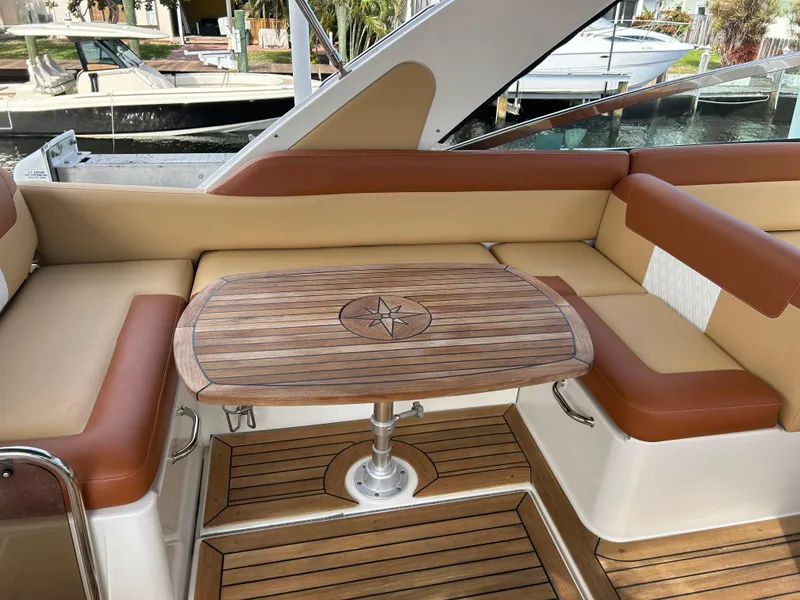 Slide: The Image of 2014 Sea Ray 370 Venture boat interior with wooden table and cushioned seating. - 38