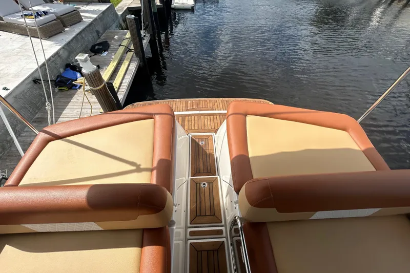 Slide: The Image of 2014 Sea Ray 370 Venture boat with cushioned seating and wooden deck at a dock. - 48