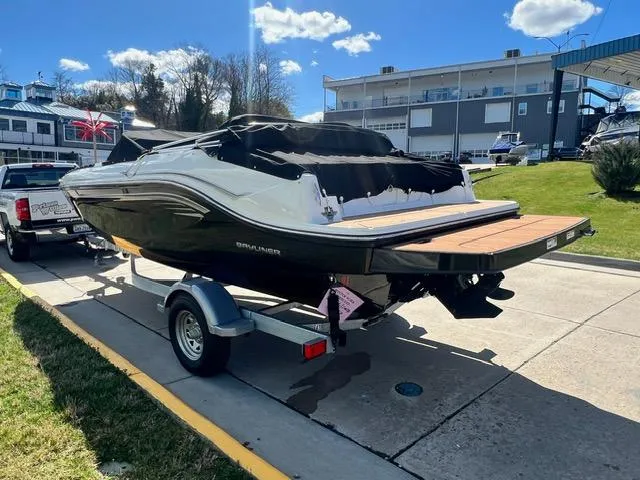 Slide: The Image of 2023 Bayliner DX 2050 boat on a trailer, parked near a marina. - 5