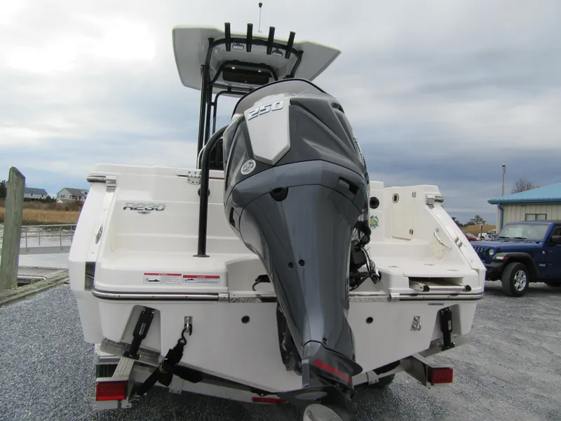 Slide: The Image of 2024 Robalo R230 Center Console boat with powerful outboard motor, docked on gravel. - 4