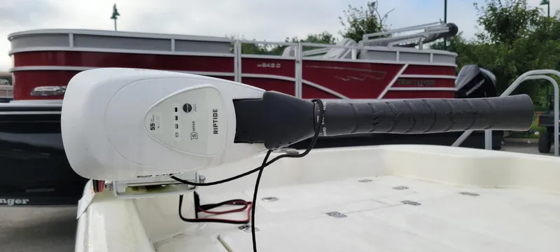 Slide: The Image of 2024 Mako Pro Skiff 15 CC with Riptide trolling motor, docked near red pontoon boat. - 2