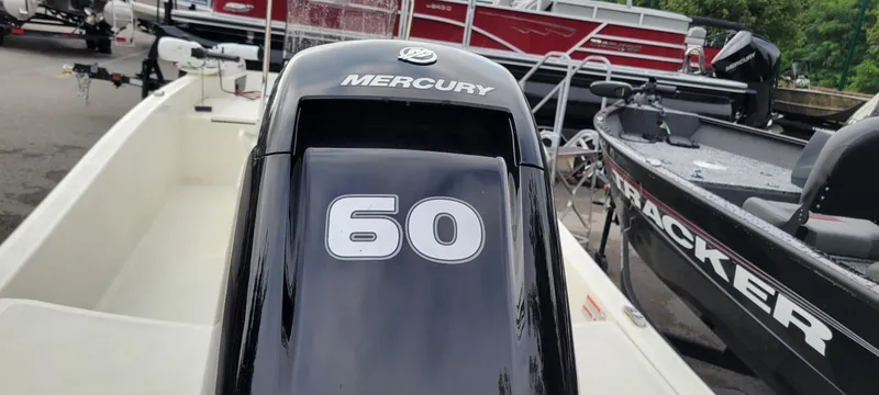 Slide: The Image of 2024 Mako Pro Skiff 15 CC with Mercury 60 engine, docked near other boats. - 5