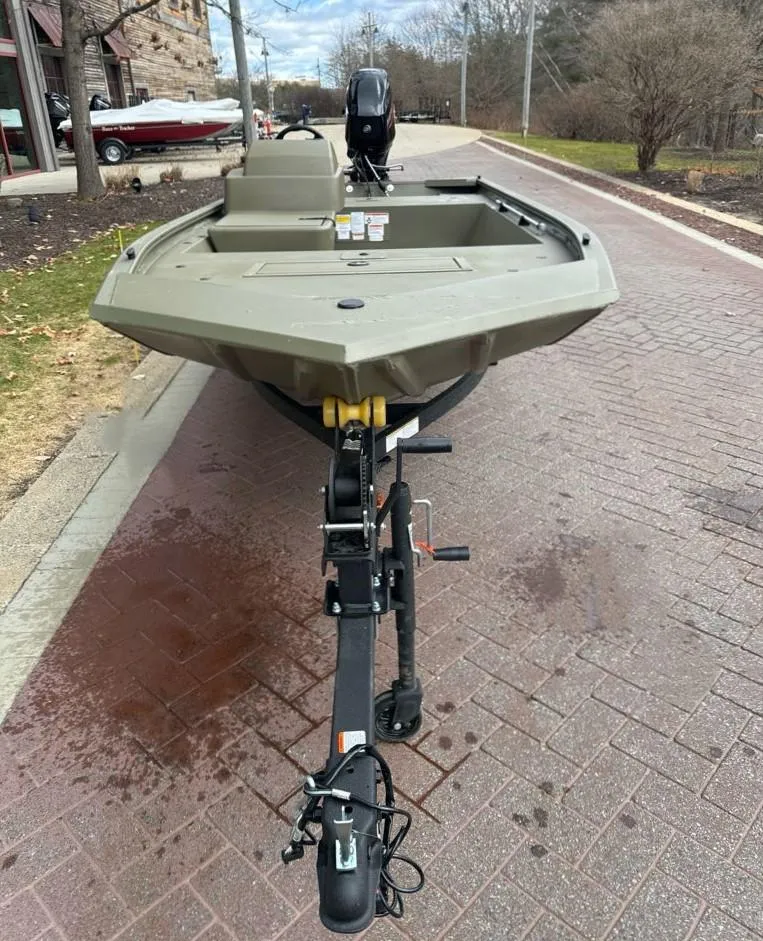 Slide: The Image of 2024 Tracker Grizzly 1648 SC boat on a trailer, parked on a brick road. - 2