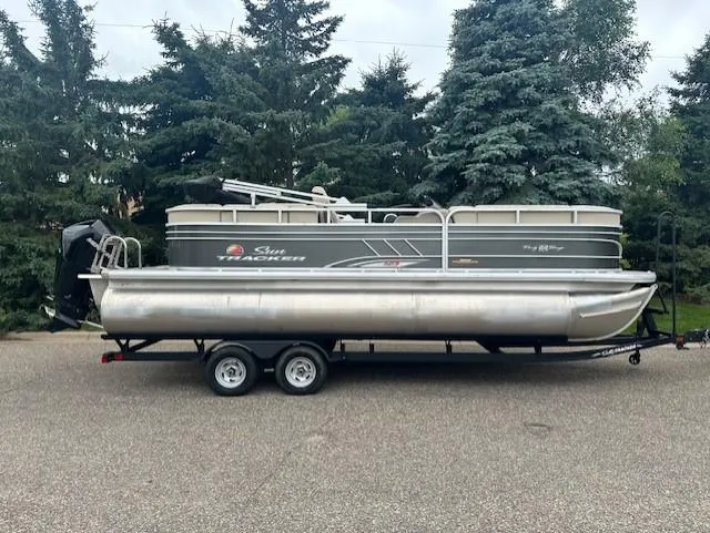 The Image of 2023 Sun Tracker Party Barge 22 XP3 pontoon boat on trailer, parked outdoors. - 0