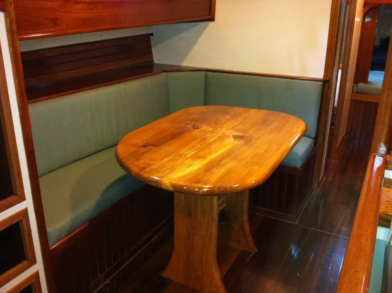 Slide: The Image of Cozy dining area with wooden table and cushioned seating on 1964 Custom 65 Pilothouse Schooner. - 7