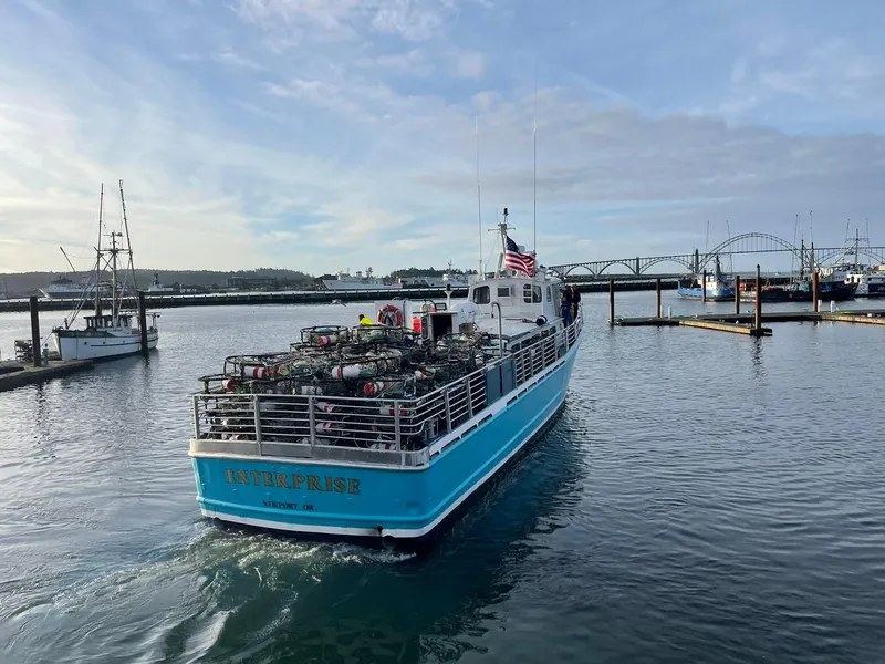 Slide: The Image of 1983 Swiftships charter boat in harbor, carrying equipment, with bridge and other boats in background. - 10