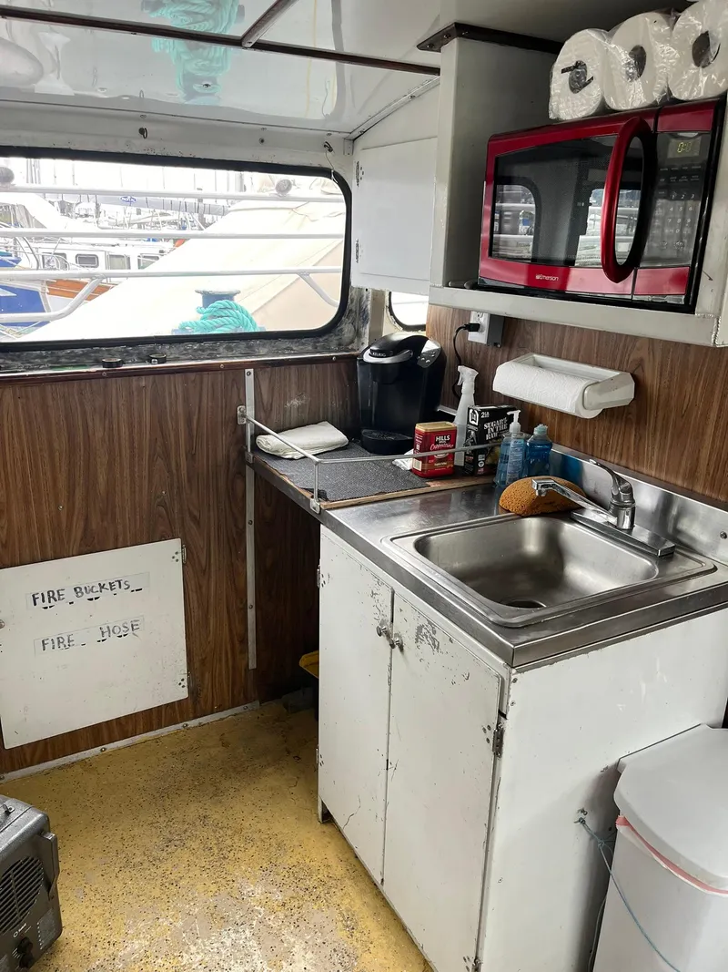 Slide: The Image of 1983 Swiftships Charter Boat kitchen with sink, microwave, and window view of marina. - 20