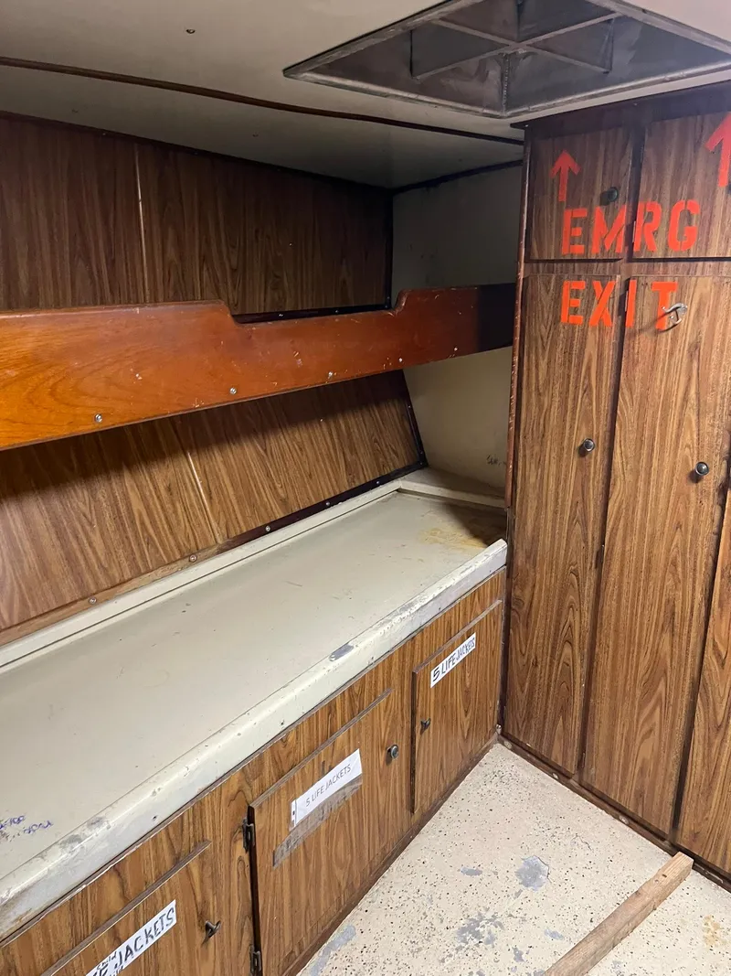 Slide: The Image of 1983 Swiftships Charter Boat interior with emergency exit and storage cabinets. - 24