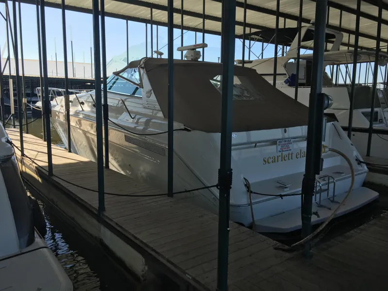 Slide: The Image of 1994 Sea Ray 500 Sundancer docked in a marina, covered with a brown canopy. - 1