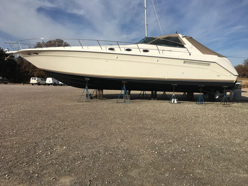 Slide: The Image of 1994 Sea Ray 500 Sundancer yacht on dry dock, beige hull, clear sky background. - 4