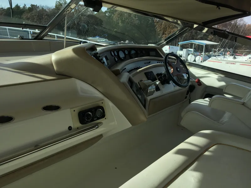 Slide: The Image of 1994 Sea Ray 500 Sundancer helm with steering wheel and control panel, docked at marina. - 7