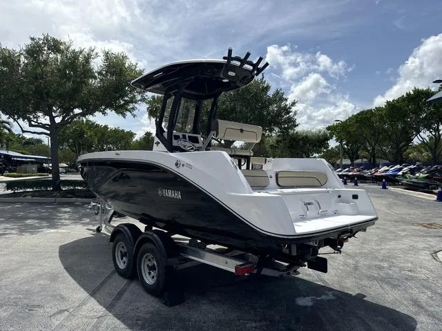 Slide: The Image of 2024 Yamaha Boats 222 FSH Sport E displayed in a showroom between two other boats. - 3