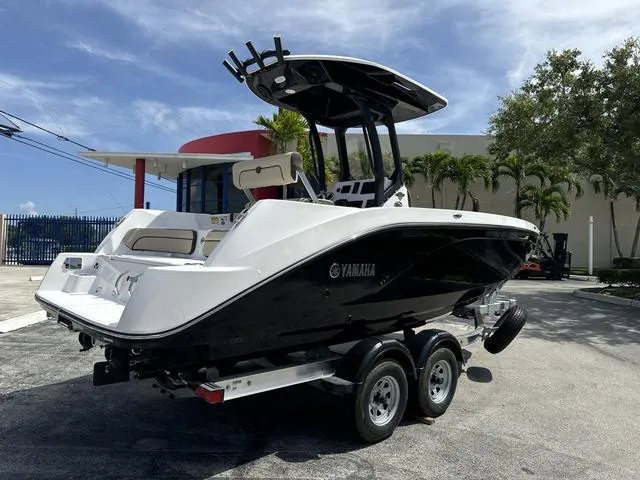 Slide: The Image of 2024 Yamaha Boats 222 FSH Sport E, sleek black and white design, docked under canopy. - 5