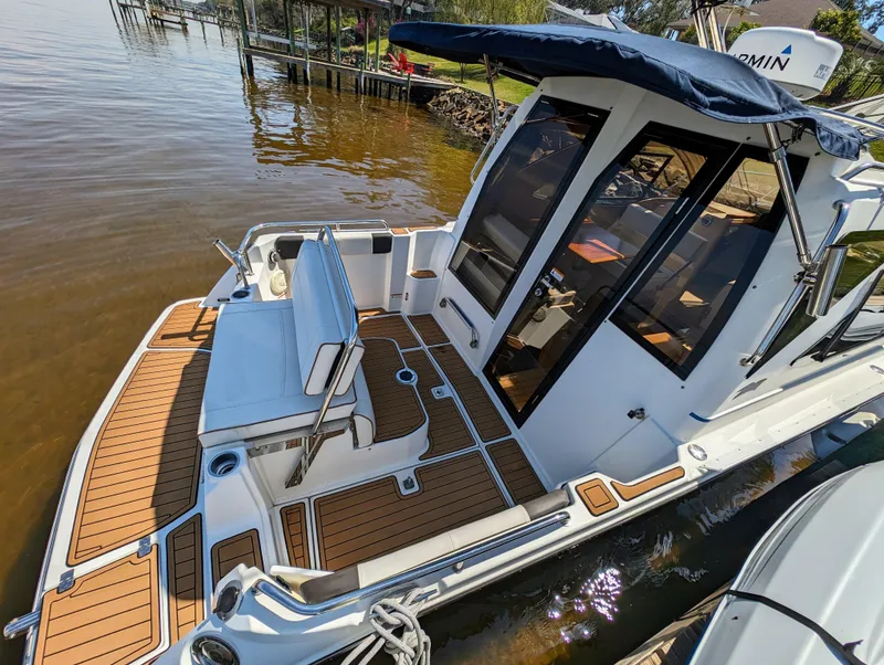 Slide: The Image of 2016 Cutwater 24 boat with teak deck and seating, docked by the water. - 6