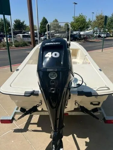 Slide: The Image of 2024 Mako Pro Skiff 13 CC boat with Mercury 40 outboard motor, parked outdoors. - 2