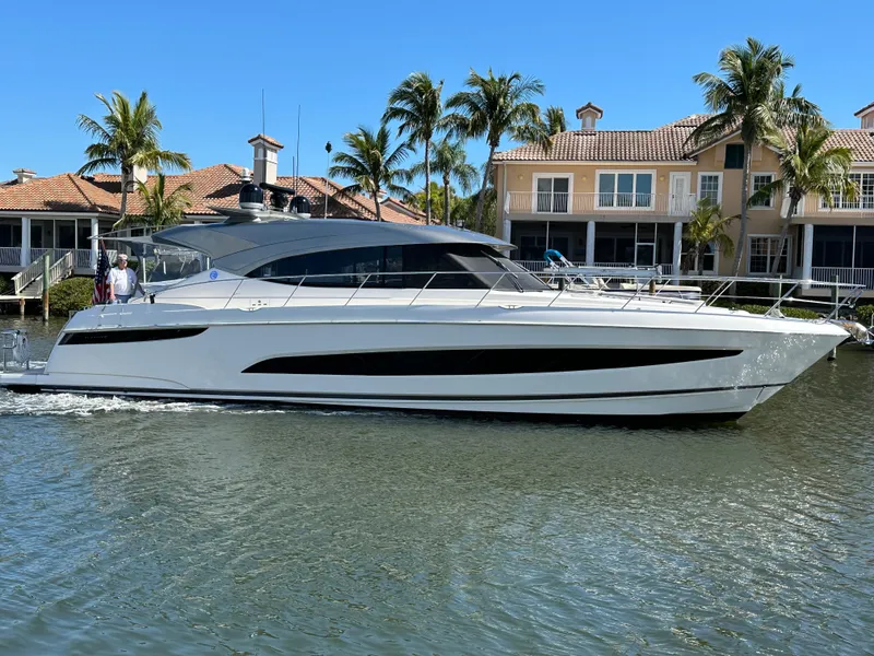 Slide: The Image of 2022 Riviera Sport Yacht 5400 Platinum Edition cruising near waterfront homes. - 0