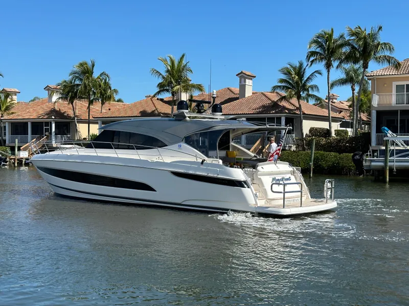Slide: The Image of 2022 Riviera Sport Yacht 5400 Platinum Edition cruising near waterfront homes. - 10