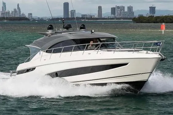 Slide: The Image of 2022 Riviera Sport Yacht 5400 Platinum Edition cruising on water with city skyline backdrop. - 11
