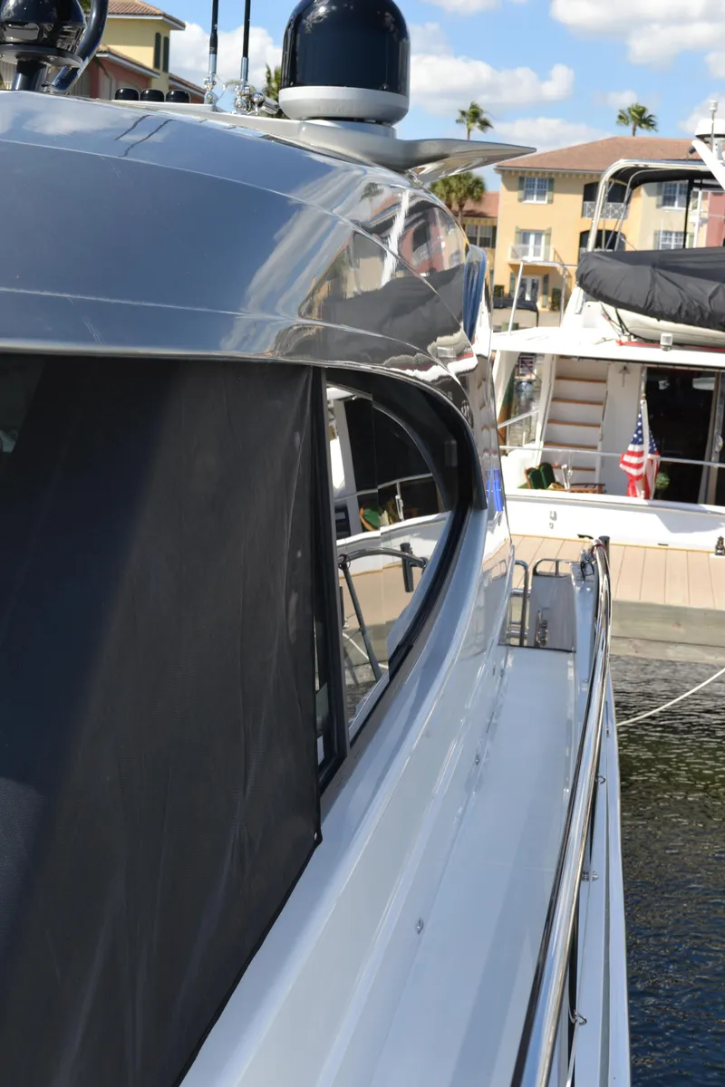 Slide: The Image of 2022 Riviera Sport Yacht 5400 Platinum Edition docked at marina, side view. - 13