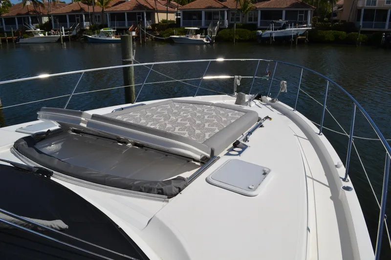 Slide: The Image of 2022 Riviera Sport Yacht 5400 Platinum Edition with sunpad, docked near waterfront homes. - 20