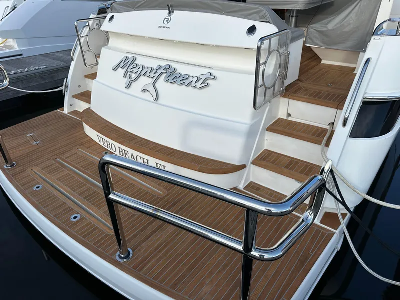 Slide: The Image of 2022 Riviera Sport Yacht 5400 Platinum Edition docked, featuring teak deck and elegant design. - 28